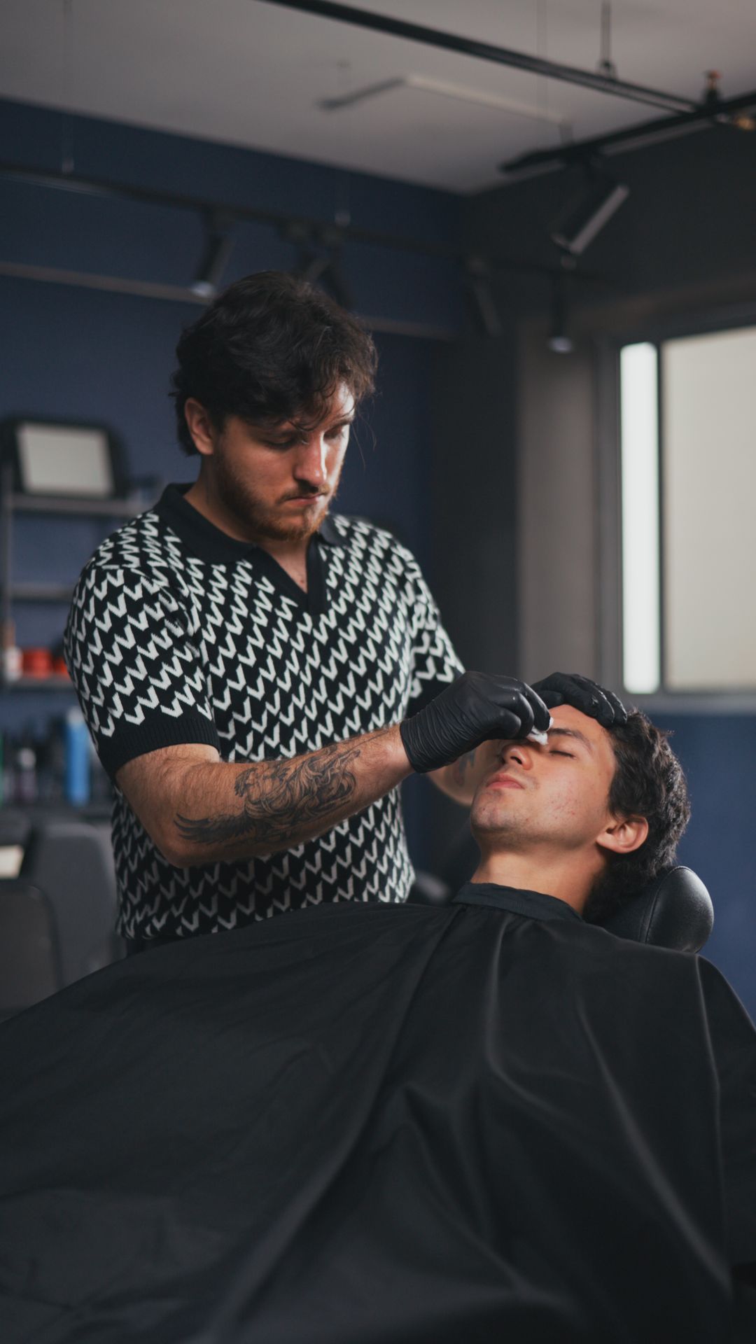 Barbero de PULSO Barber Studios trabajando el rostro de un cliente en el sillón