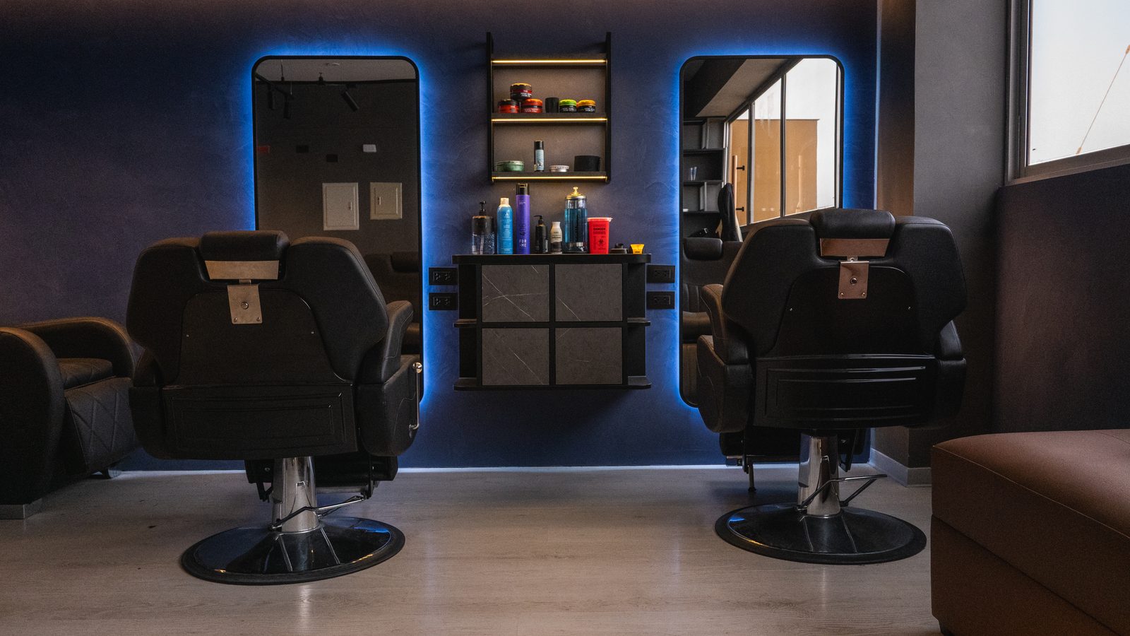 Estaciones de trabajo de PULSO Barber Studios, con espejos iluminados y sillones de barbería